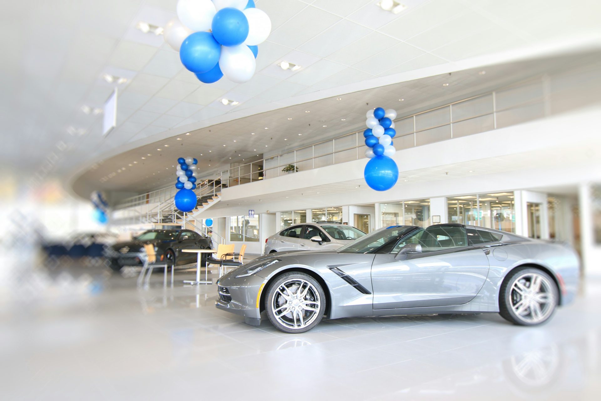 ein silberner Sportwagen in einem Ausstellungsraum mit blauen und weißen Luftballons